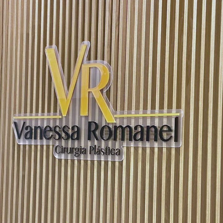 Logo VR Vanessa Romanel Cirurgia Plástica aplicado na parede de madeira ripada