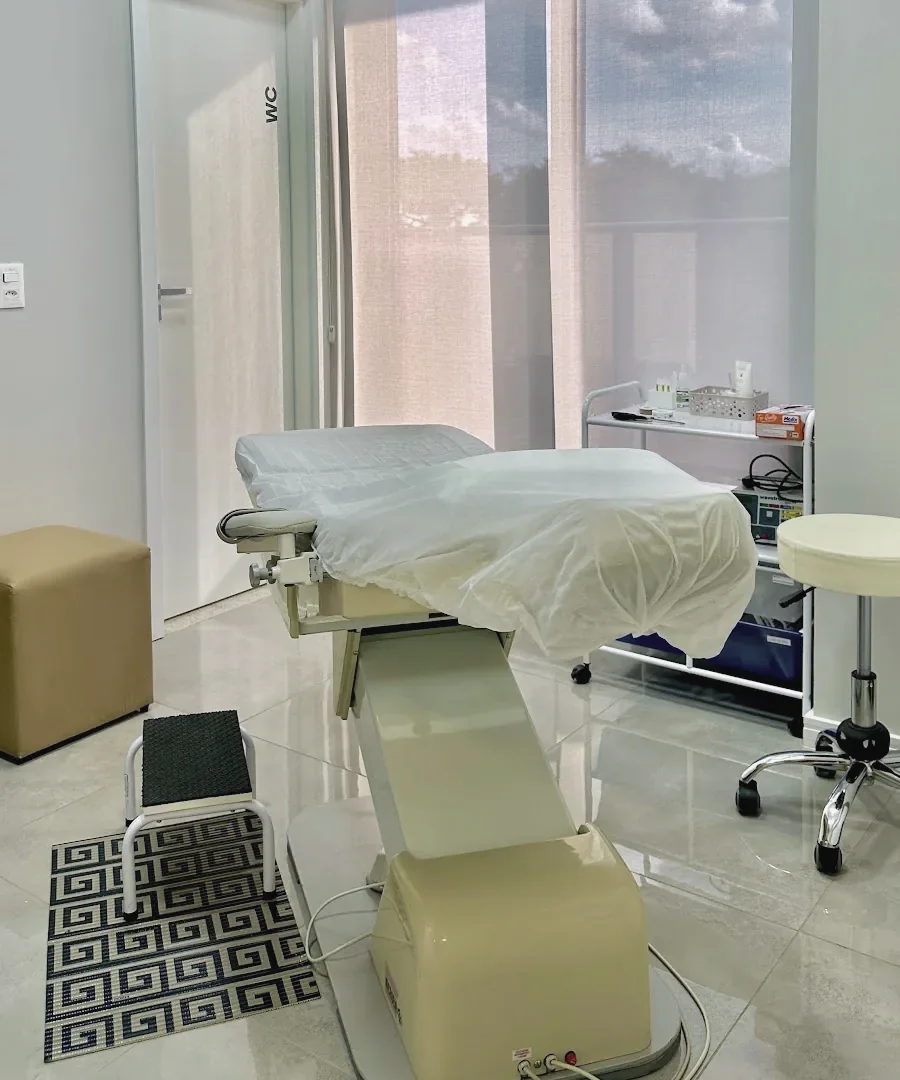 Sala de procedimento com maca, janela ampla e piso claro