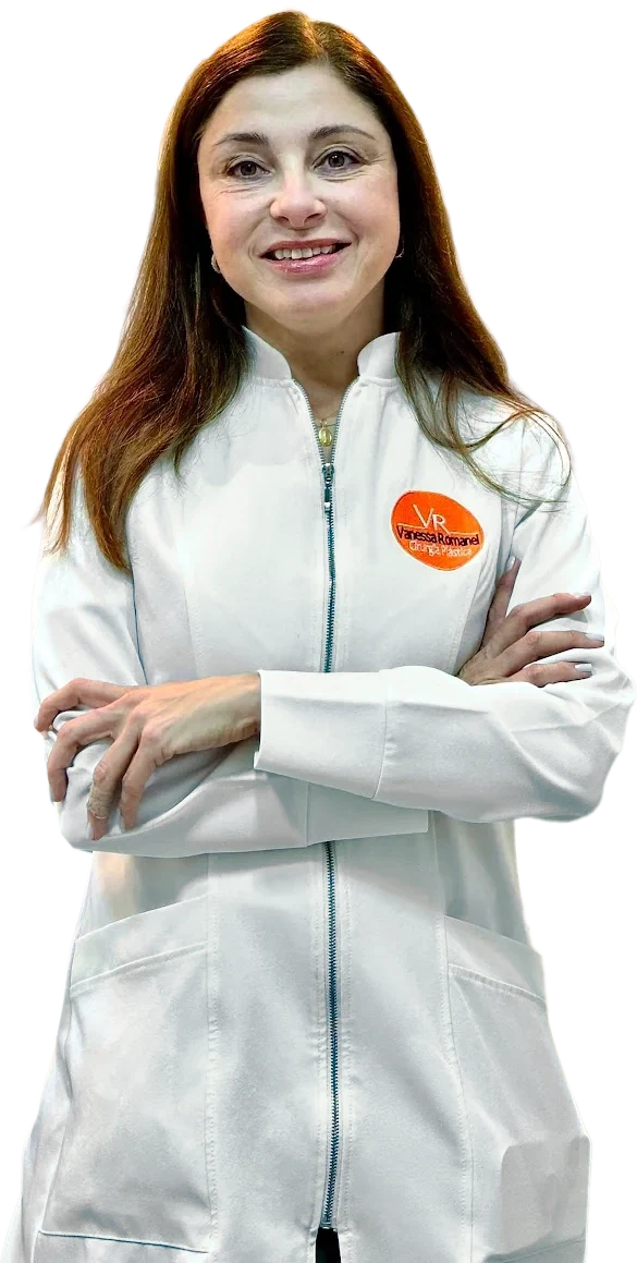 Dra. Vanessa Romanel de jaleco branco com o monograma VR, de braços cruzados, sorrindo